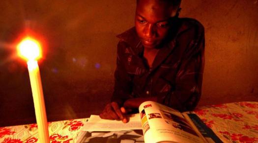 由于津巴布韦缺电，学生们经常要在烛光下阅读完成家庭作业。