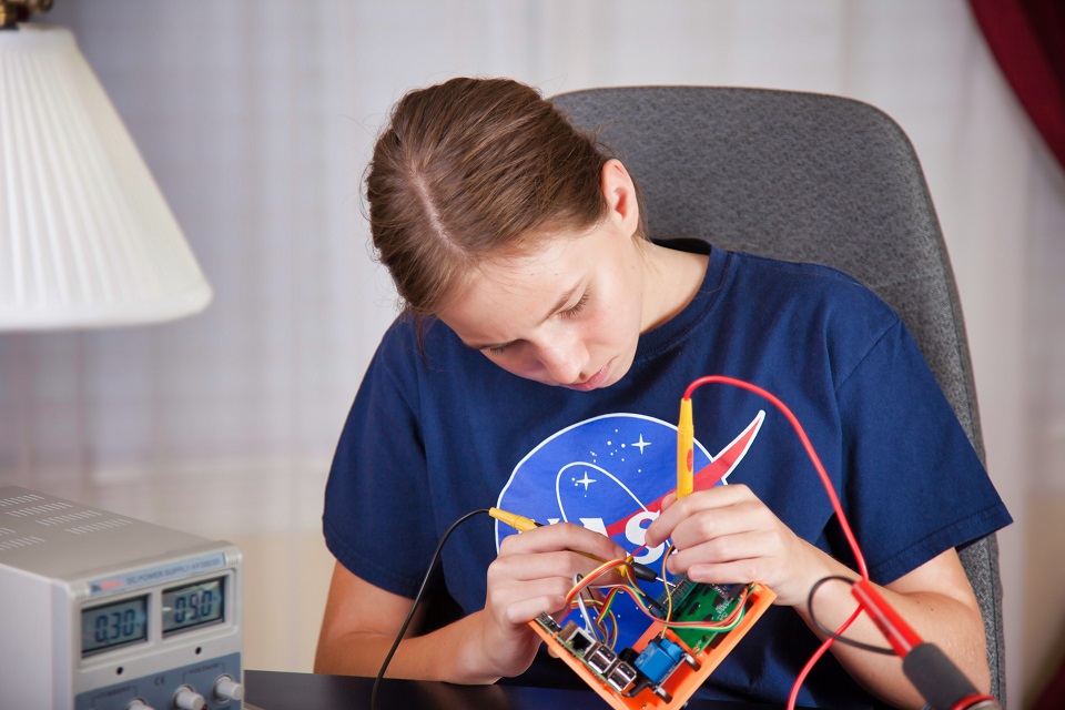 穿着蓝色NASA t恤的学生正在为一个项目处理电线