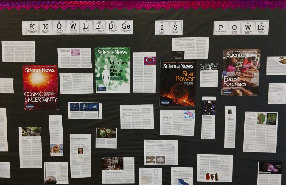 一个课堂公告板，标题读书，“知识是力量”，科学新闻文章张贴了下面