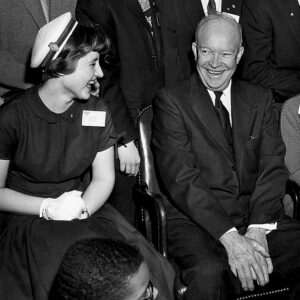 1955年德怀特·艾森豪威尔总统访问STS 1955决赛选手卡罗尔·麦凯(左)和罗伯塔·科尔曼(右)。在她的研究项目中，麦凯开发了自己的疫苗，以测试小鼠是否能成功接种流感疫苗